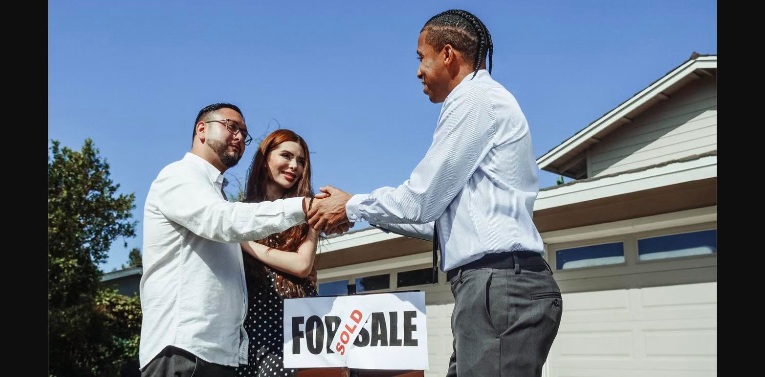 Agent commercial indépendant Izy Immobilier serrant la main de ses clients devant leur maison vendue